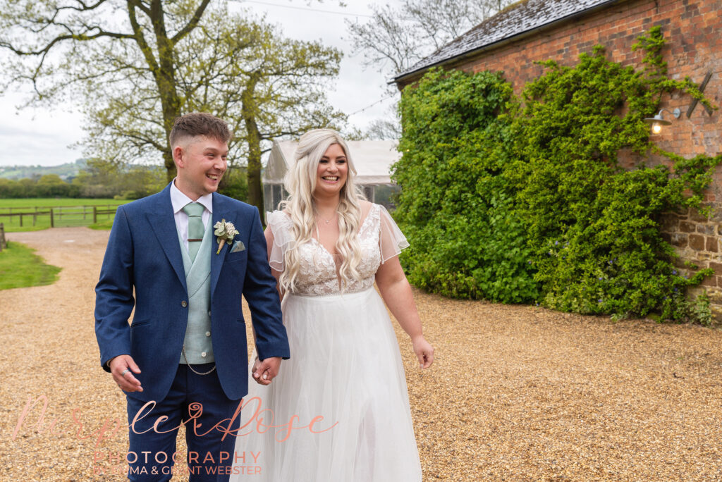 Bride and groom walking hand in hand on their wedding day in Northampton