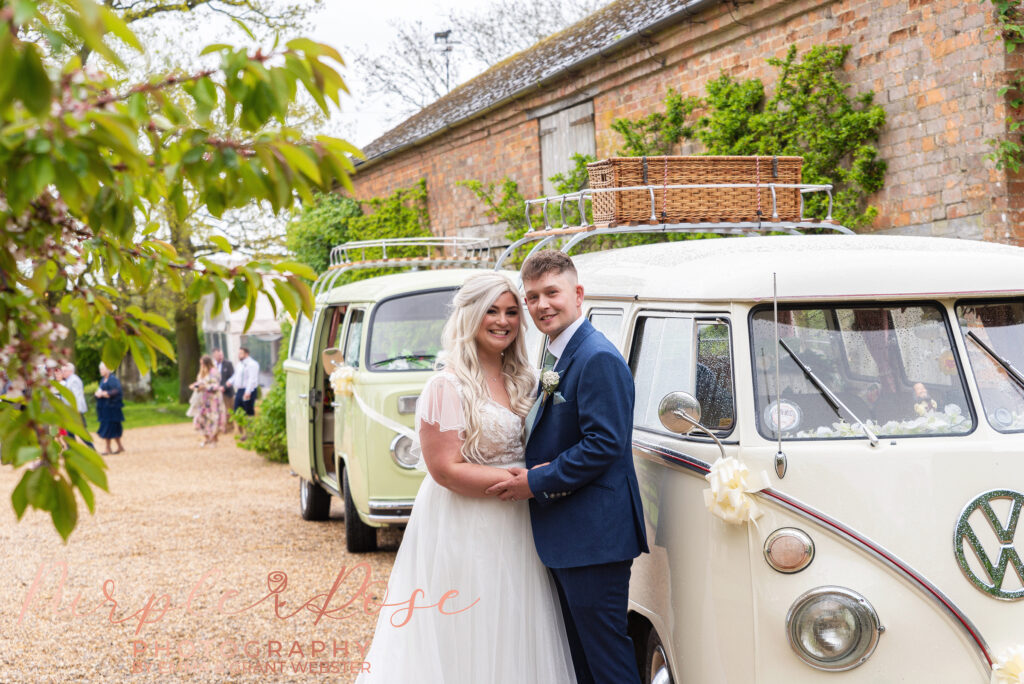 Photo of bride and groom stood by a VW camper van on their wedding day in Northampton