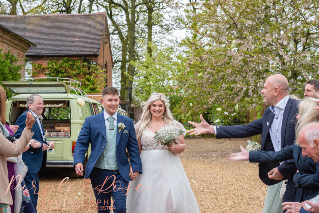 Photo of wedding guests throwing ocnfetti at the bride and groom on their wedding day in Northampton