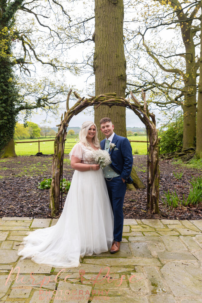 Photo of bride and groom standing in front of an archway on their wedding day in Northampton