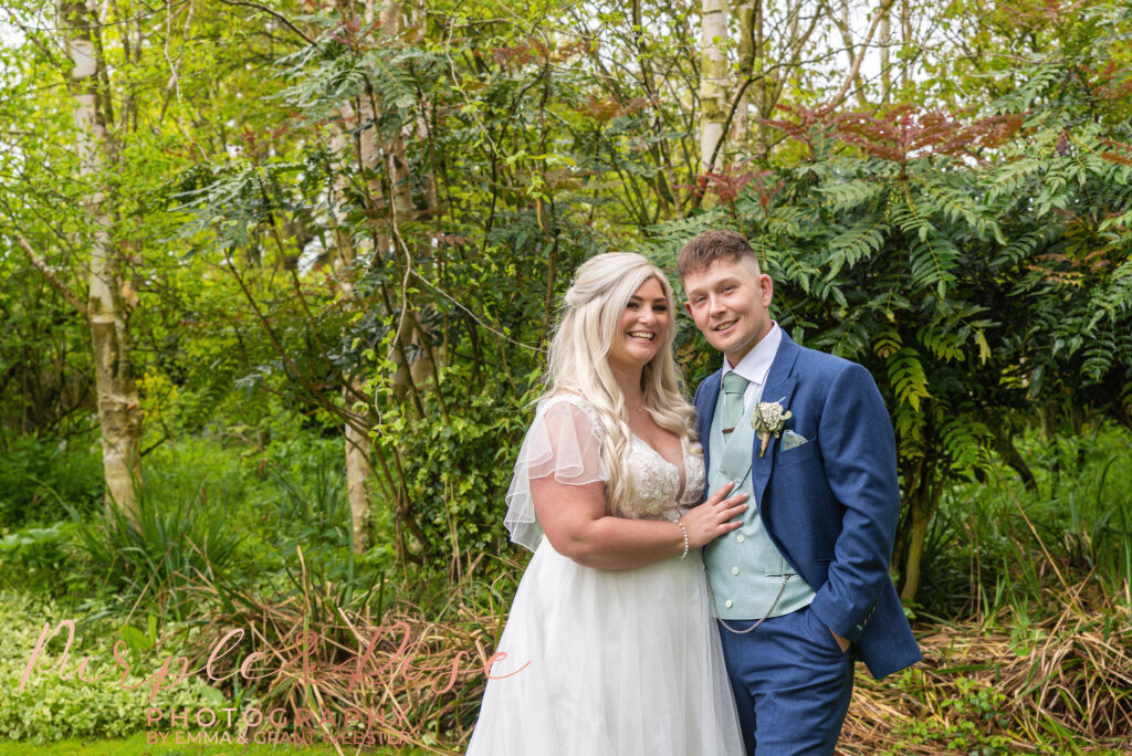 Photo of a  bride and groom stood in their wedding venues garden on their wedding day