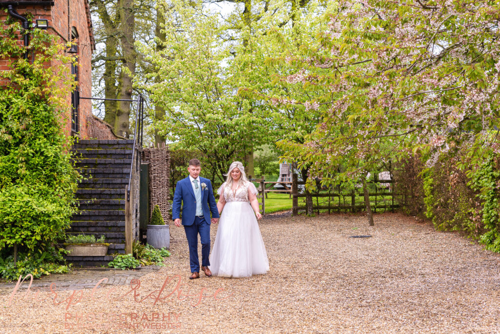 Bride and groom walking hand in hand on their wedding day in Northampton