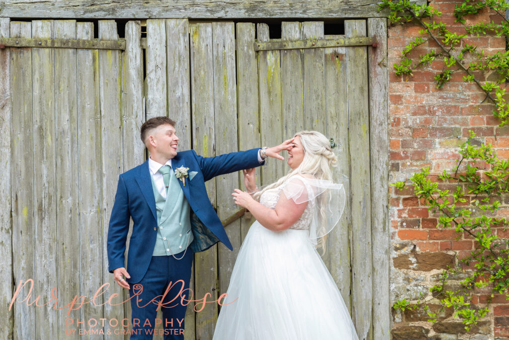 Bride and groom messing around in front of a barn door on ther wedding day in Northampton