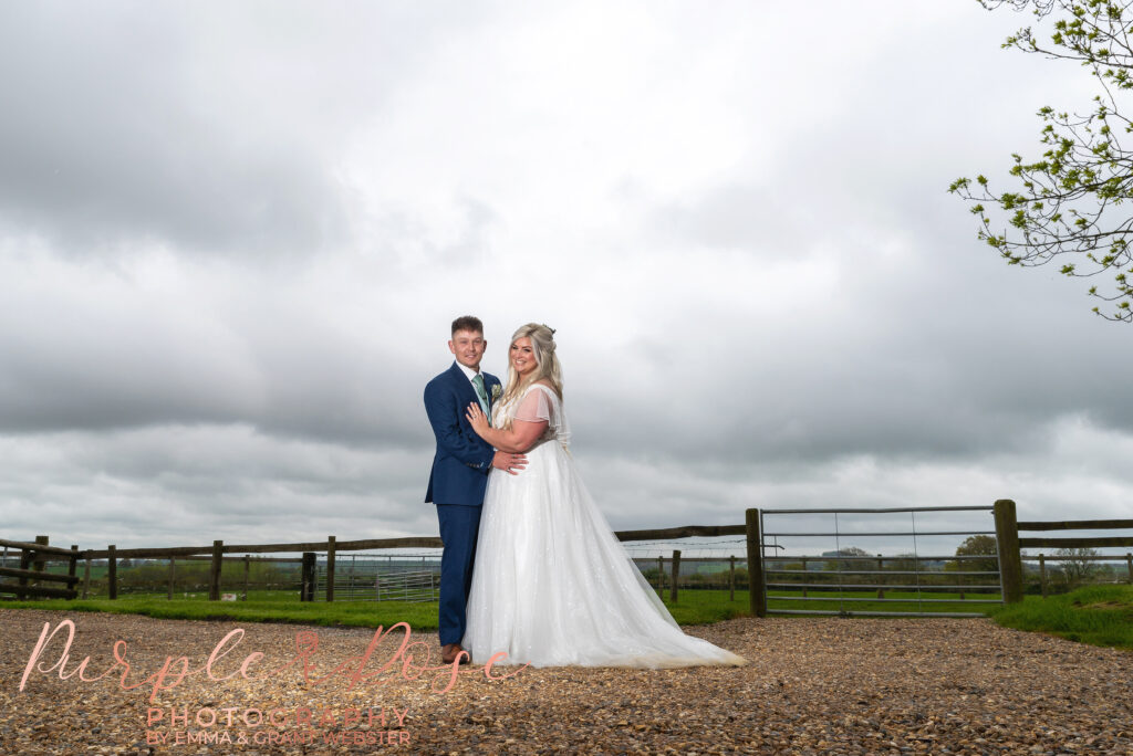 Photo of bride and groom in front of a stormy sky on their wedding day in Northampton