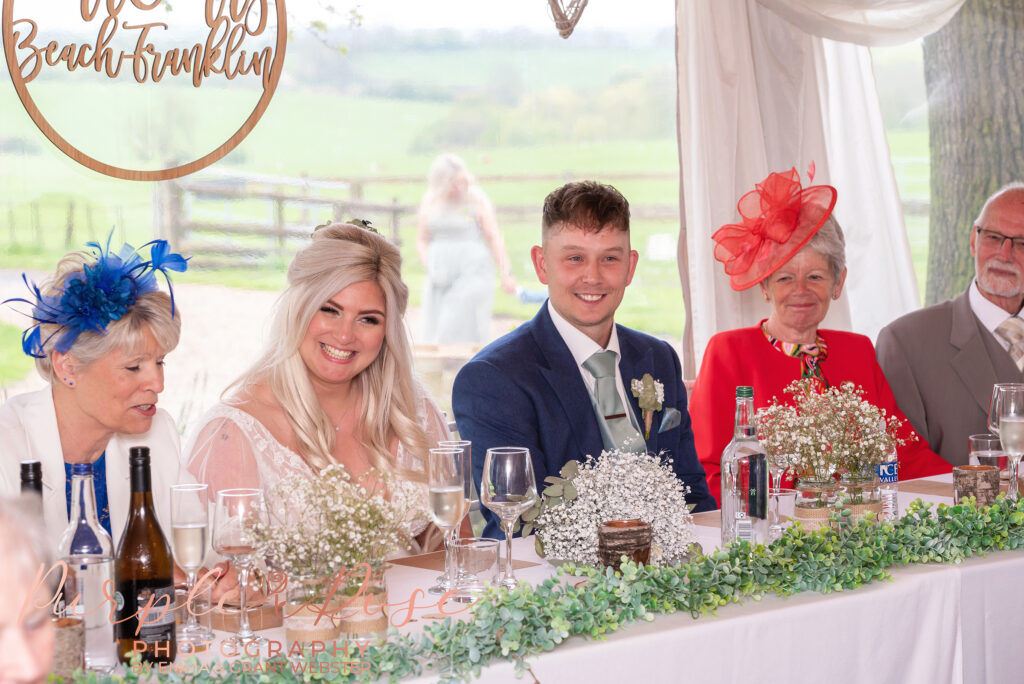 Photo of bride and groom laughing during dpeeches on their wedding day in Northampton