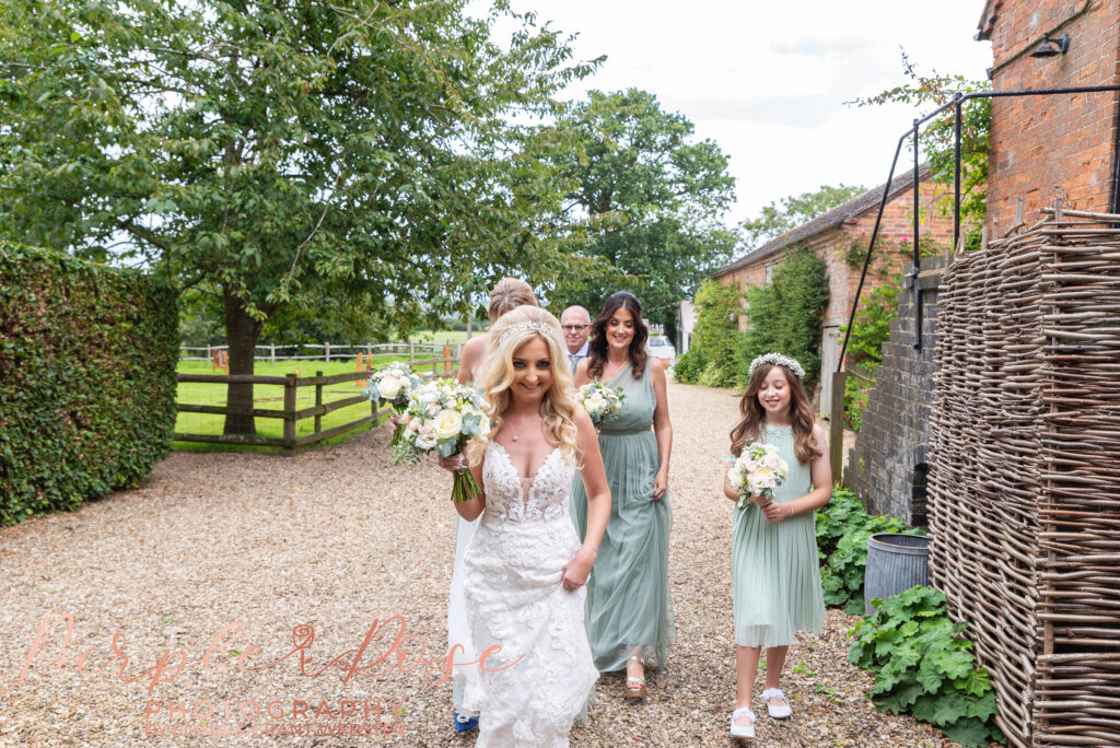 Photo of bride and bridesmaiids walking to wedding ceremony in Northampton