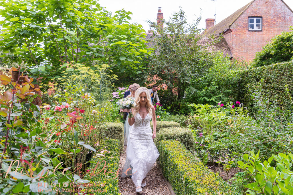 Photo of bride walking through gardens on her wedding day in Northampton