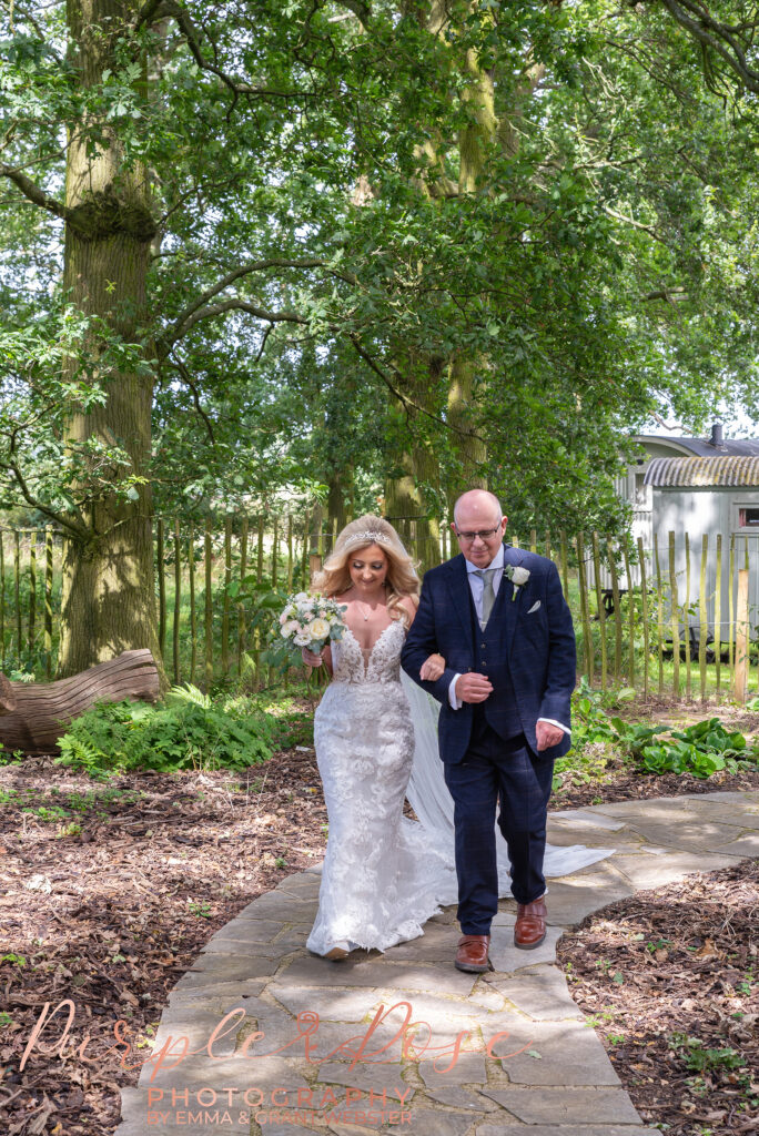 Photo of bride walking arm in arm with her father on her wedding day in Northampton