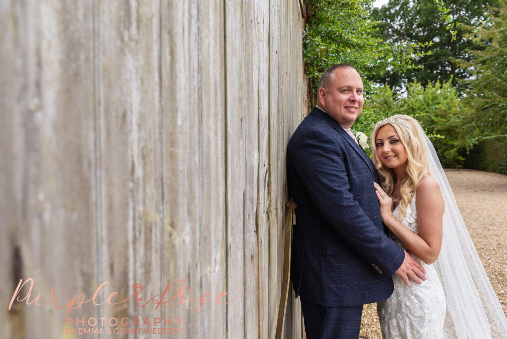 Photo of bride and groom leaning on a barn door on theri wedding day in Northampton