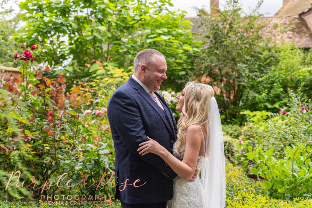 Bride and groom stood arm in arm in a garden on their wedding day in Northampton