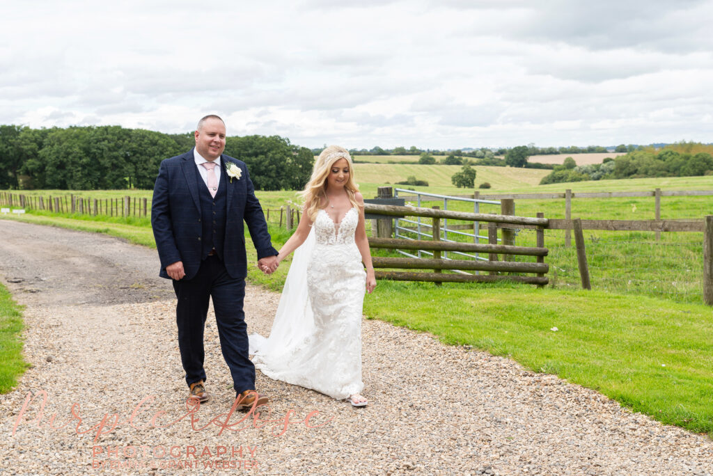 Photo of bride and groom walking hand hand in hand on their wedding day in Northampton