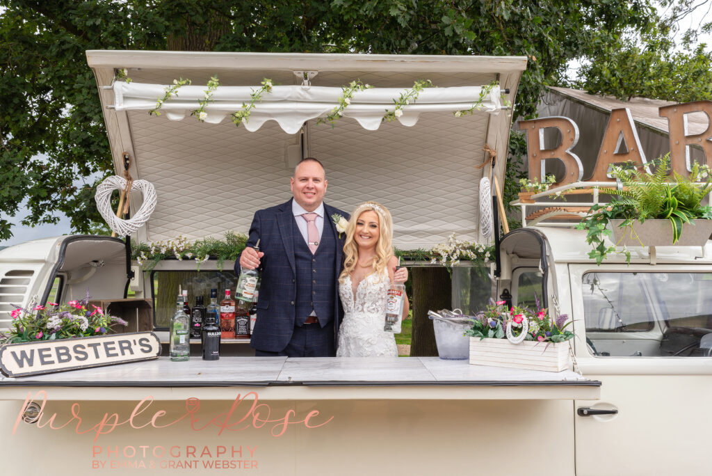 Photo of bride and groom stood in mobile bar on their wedding day in Northampton
