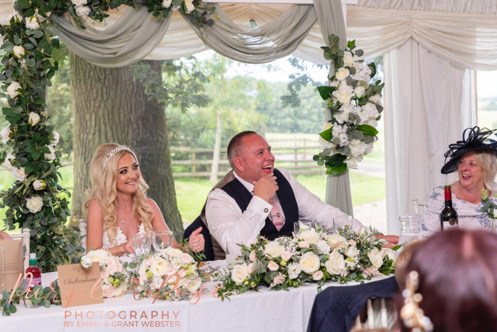 Photo of bride and groom laughing during speeches on their wedding day in Northampton