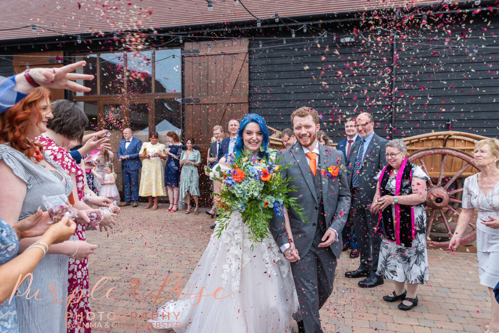 Photo of bride and groom wlaking as their wedding guests throw confetti on their wedding day in Milton Keynes