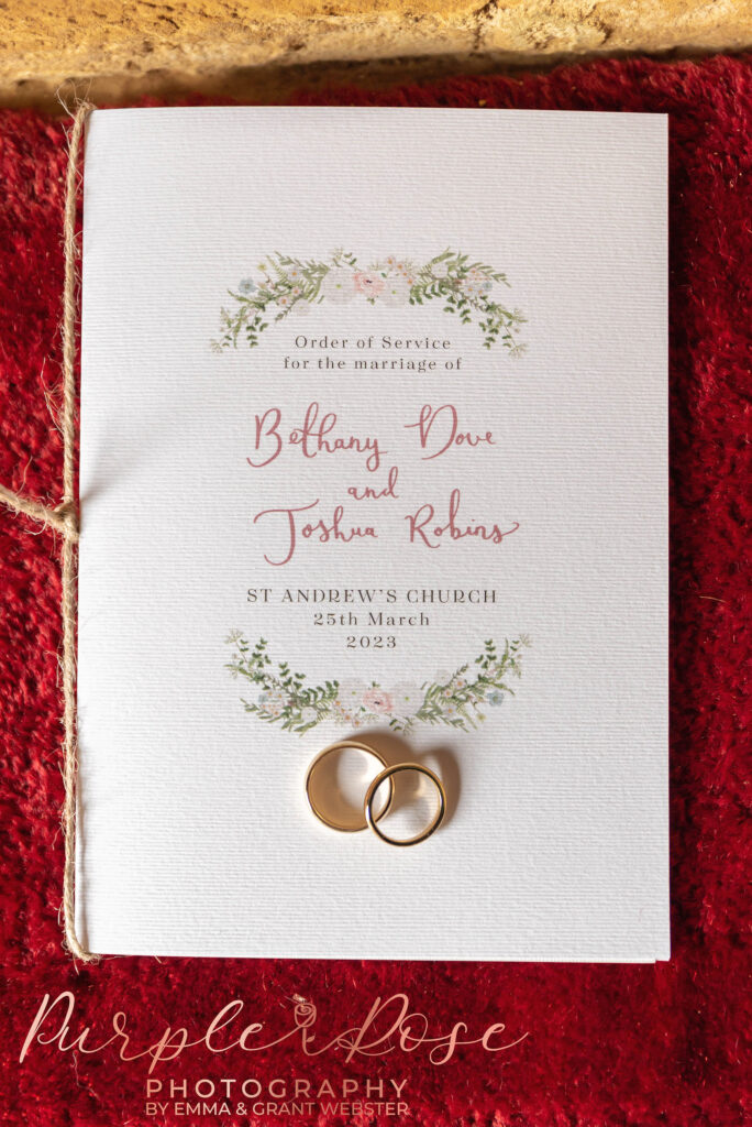 Photo of bride and grooms wedding program and wedding rings on their wedding day