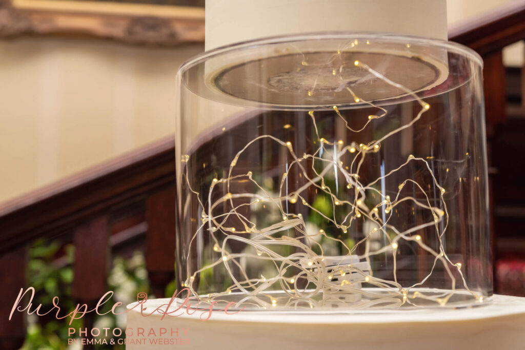 Photo of the middle layer of a wedding cake filled with fairy lights at a wedding in Milton keynes