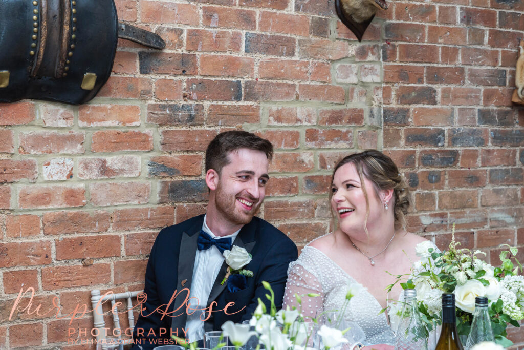 Photo of bride and groom laughing during their wedding speeches in Milton Keynes