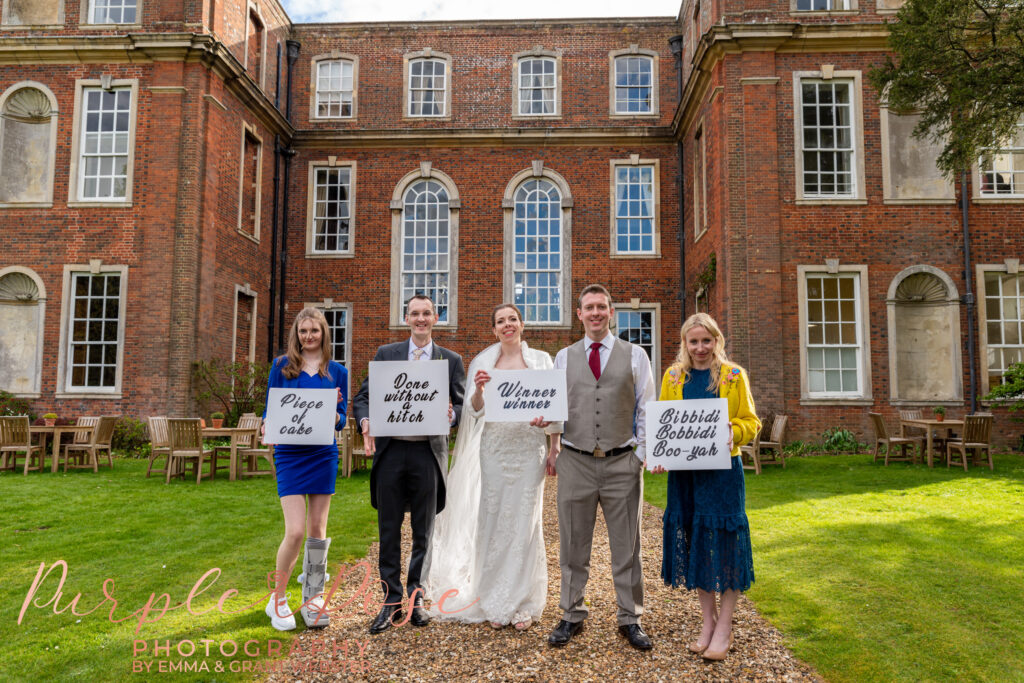 Photo of bride, grom and wedding guests holding signs at a wedding in Milton Keynes