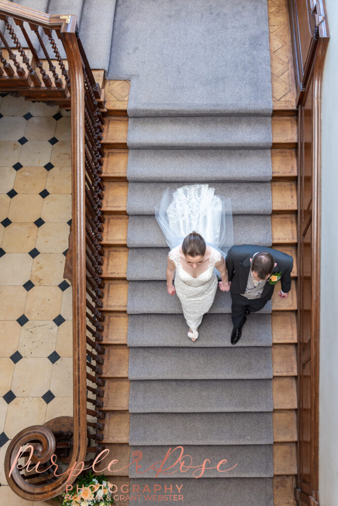 Photo of a bride and groom walking hand in hand down a staircase in Milton Keynes